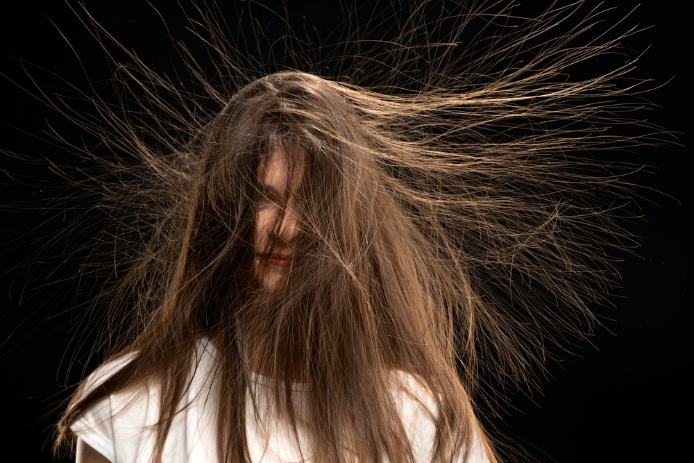 A young woman standing in her home with her hair affected by static electricity, standing on end