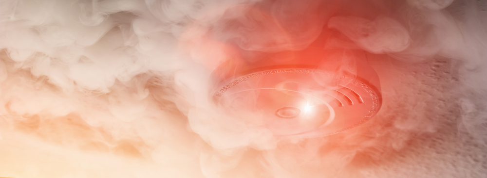 A plume of smoke swirls around a smoke detector